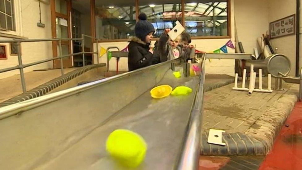 Children sending objects down a metal water chute