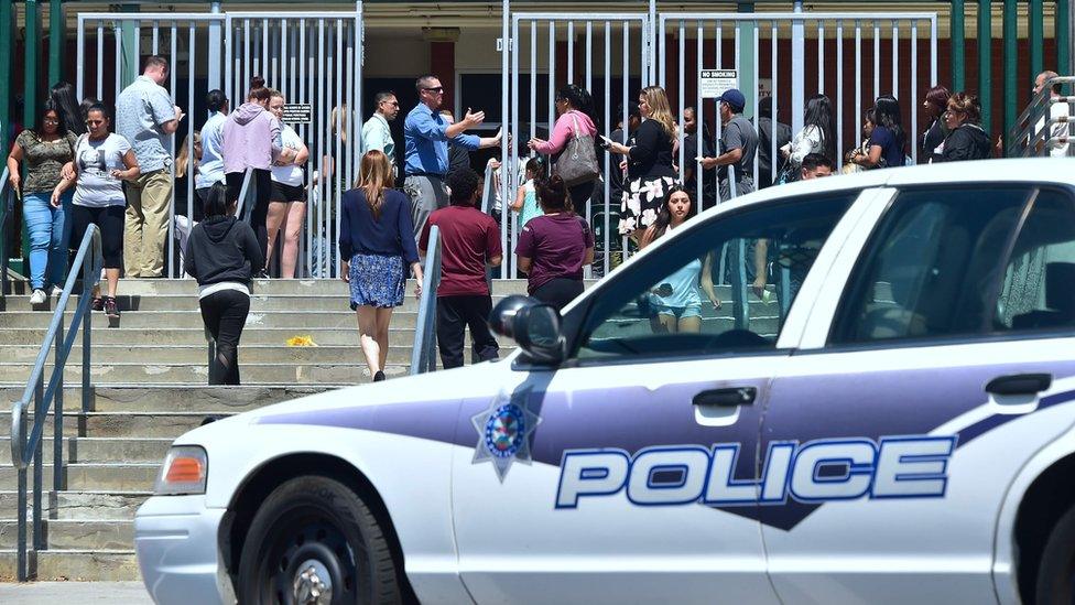 Police at Cajon High School in San Bernardino, California, help parents to locate their children following a shooting at North Park Elementary School, 10 April 2017