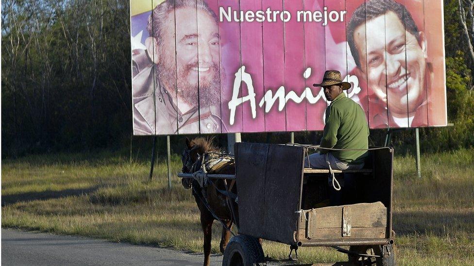 A man rides a horse-drawn cart near a poster