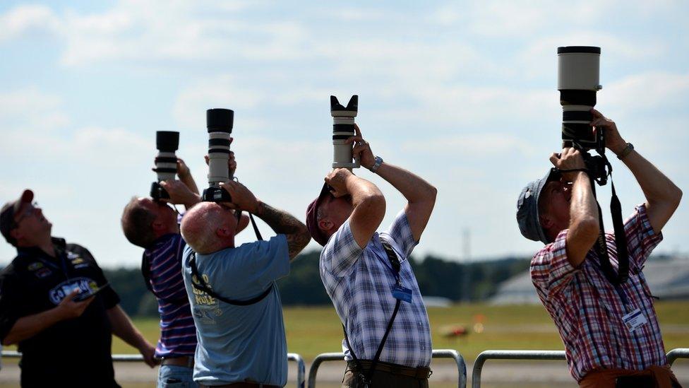 Aircraft enthusiasts photograph an air display at the Farnborough air show