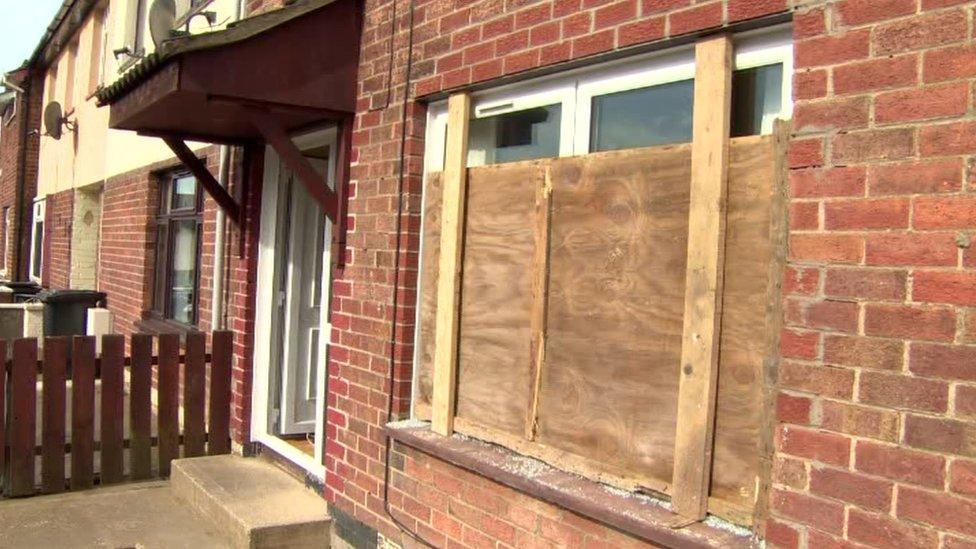 Window boarded up after it was smashed with brick