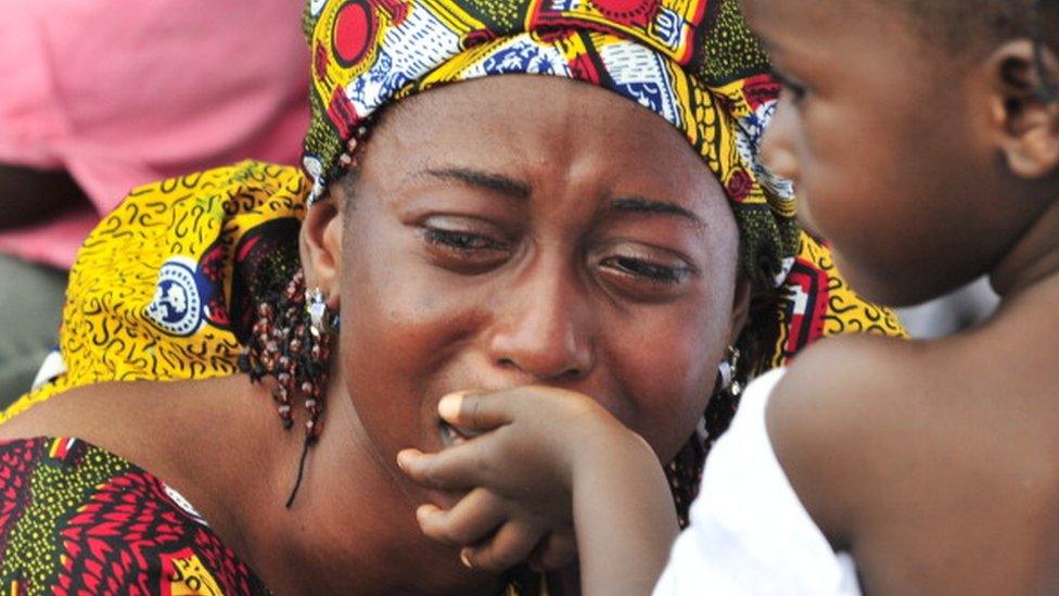 A young girl tries to comfort her mother during a burial ceremony for victims of the post-election violence at the municipal cemetery of Abobo in Abidjan on October 13, 2011