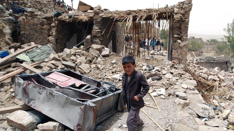 A Yemeni boy walks past the rubble of destroyed houses in the village of Bani Matar, about 70km west of Sanaa, on 4 April 2015,