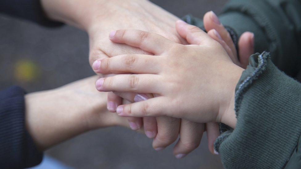 Children and adult hold hands