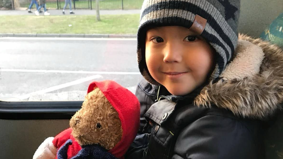 William Gray in a hat and coat, holding a teddy bear