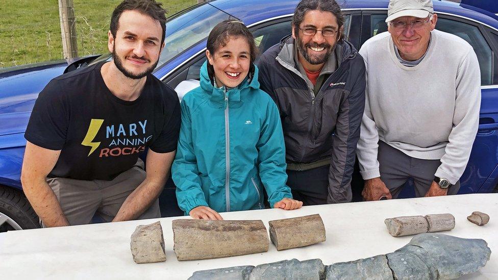 Ruby, her dad and two scientists with pieces of the fossil they have found.