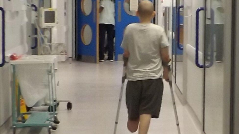 Alfie walking on crutches in hospital