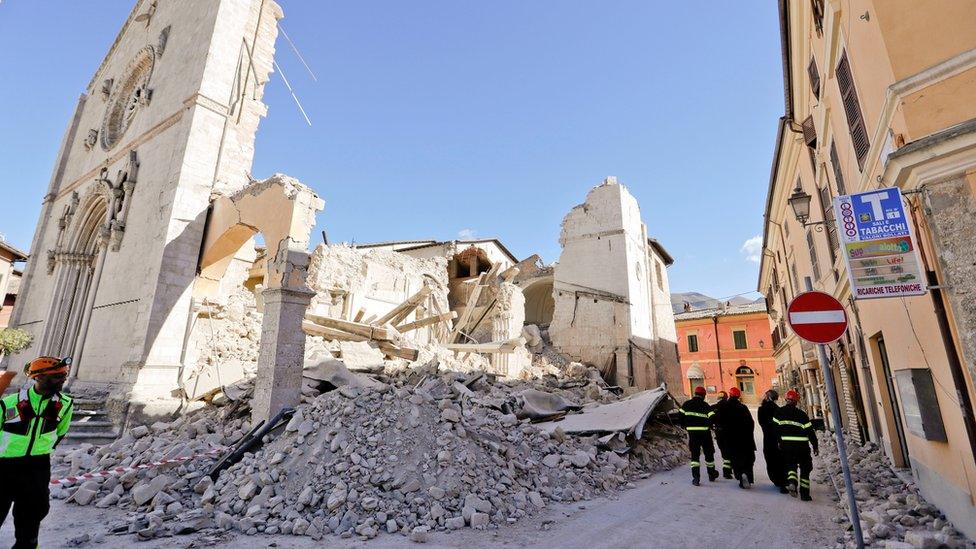 Monks walk in front of the collapsed Cathedral of St. Benedict in Norcia, central Italy