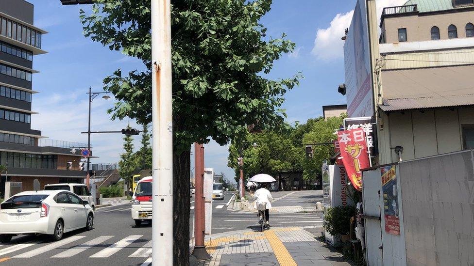 A cyclist rides with a parasol in Koshigaya