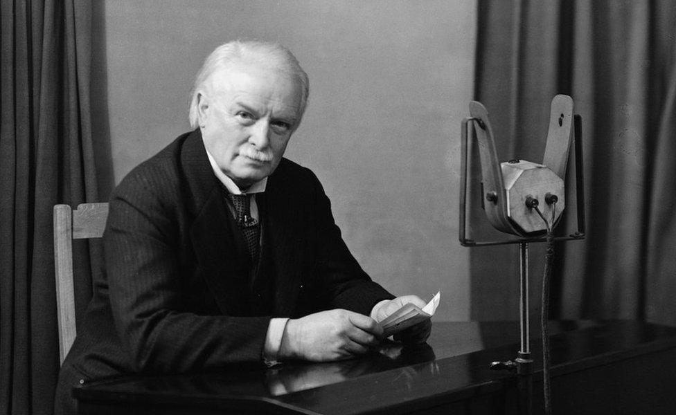 David Lloyd George sitting at a microphone