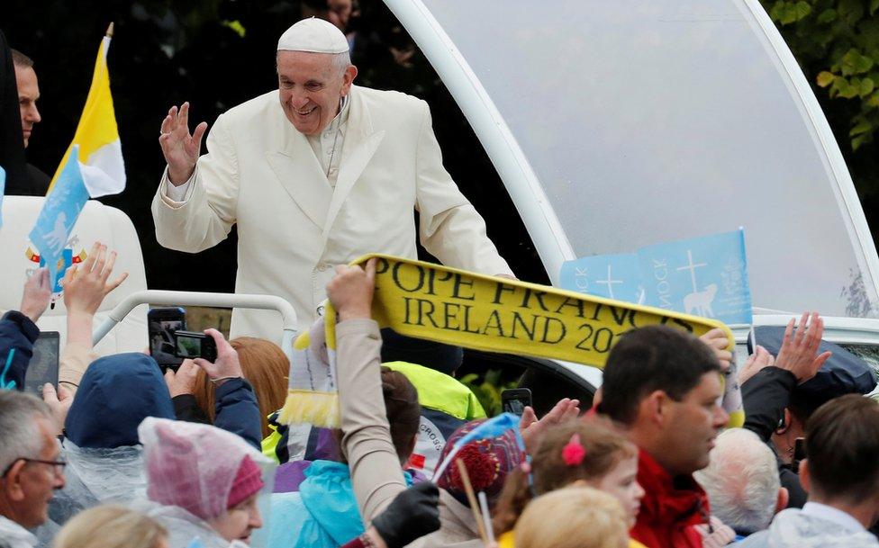 Pope Francis waves to the crowd as he travels in the popemobile to the Knock shrine