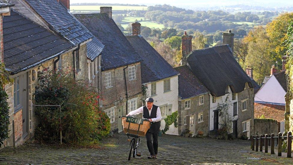 Carl Barlow pushes a bike up a steep cobbled street