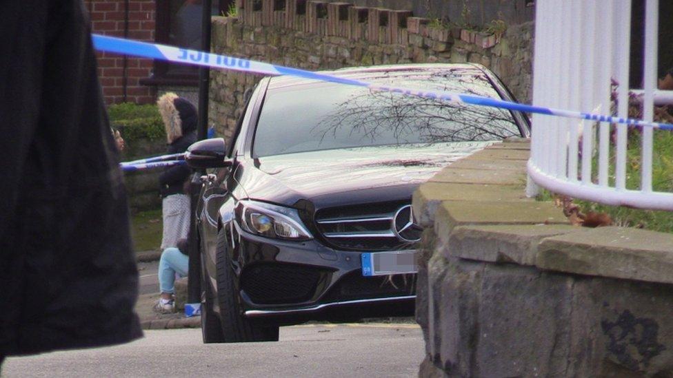 Police tape around a black car