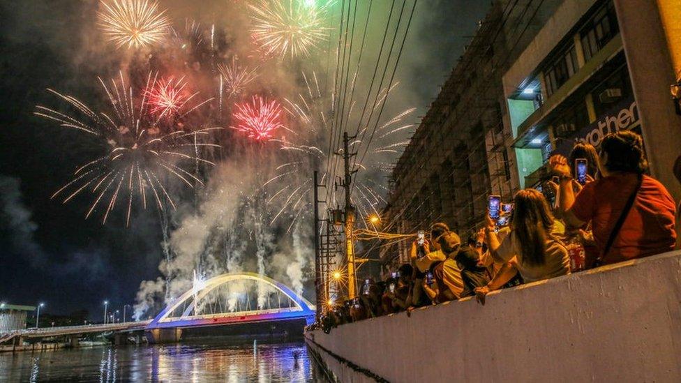 Revelers watch as the fireworks explode over the Binondo-Intramuros bridge in Manila during the Lunar New Year of the Rabbit. People celebrate the traditional Lunar New Year at Chinatown in Manila after a two-year hiatus due to the Covid-19 pandemic.