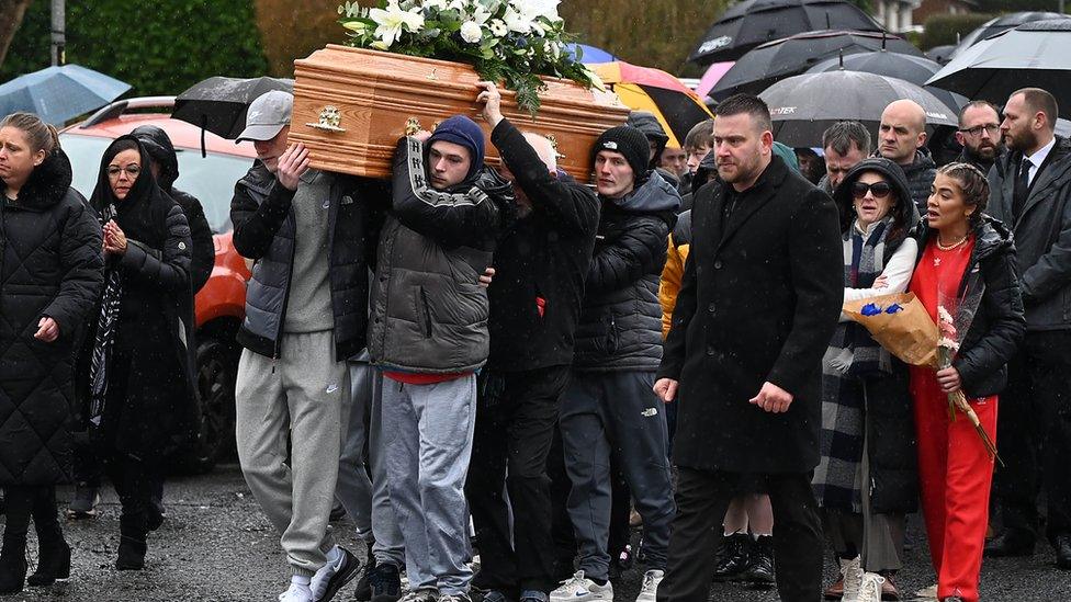 Shows mourners carrying Blake Newland's coffin