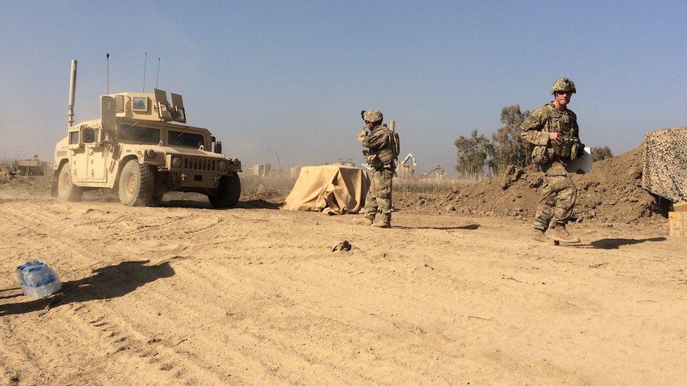 Two US soldiers are seen near a military vehicle