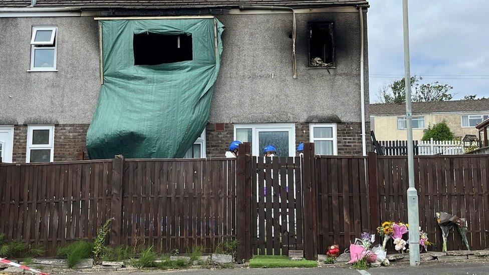 Floral tributes are seen outside the property in Swansea on Sunday