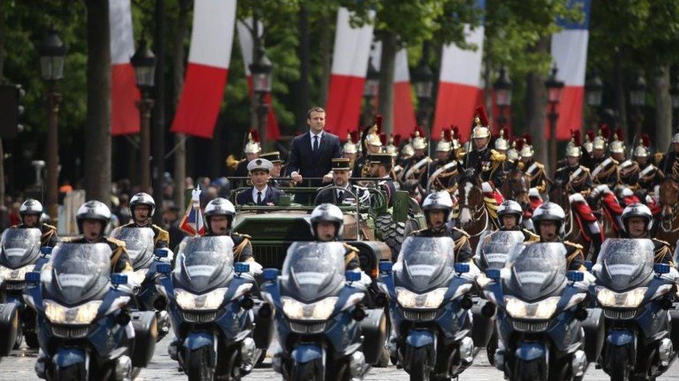 French President Emmanuel Macron waves as he parades in a car on the Champs Elysees avenue after his formal inauguration ceremony as French President on 14 May 2017 in Paris