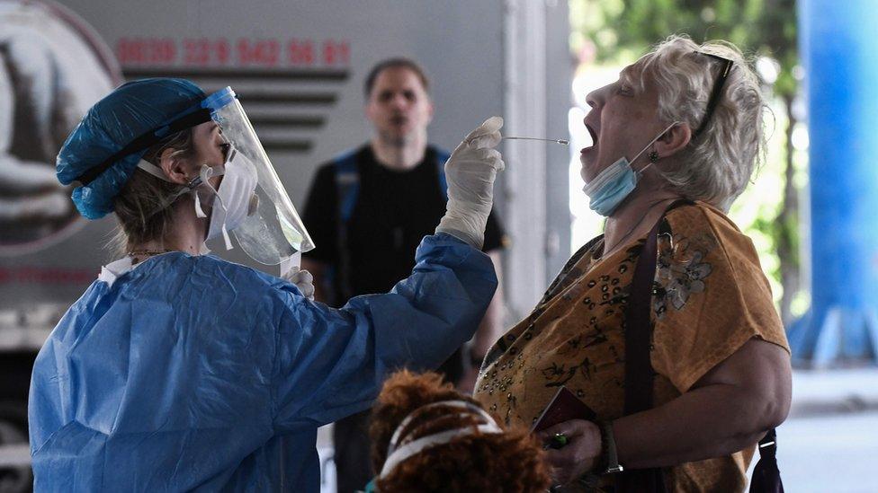 A public health worker collects a swab sample from a woman to test for the COVID-19 coronavirus at the Greek-Bulgarian border crossing in Promachonas on June 19, 2020