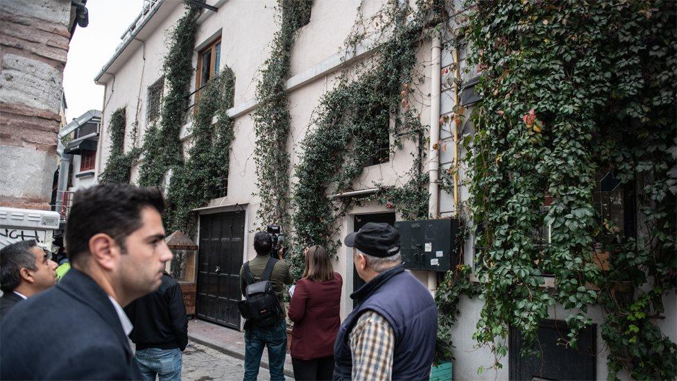 Journalists look at the apartment building from which James Le Mesurier fell to his death (11 November 2019)