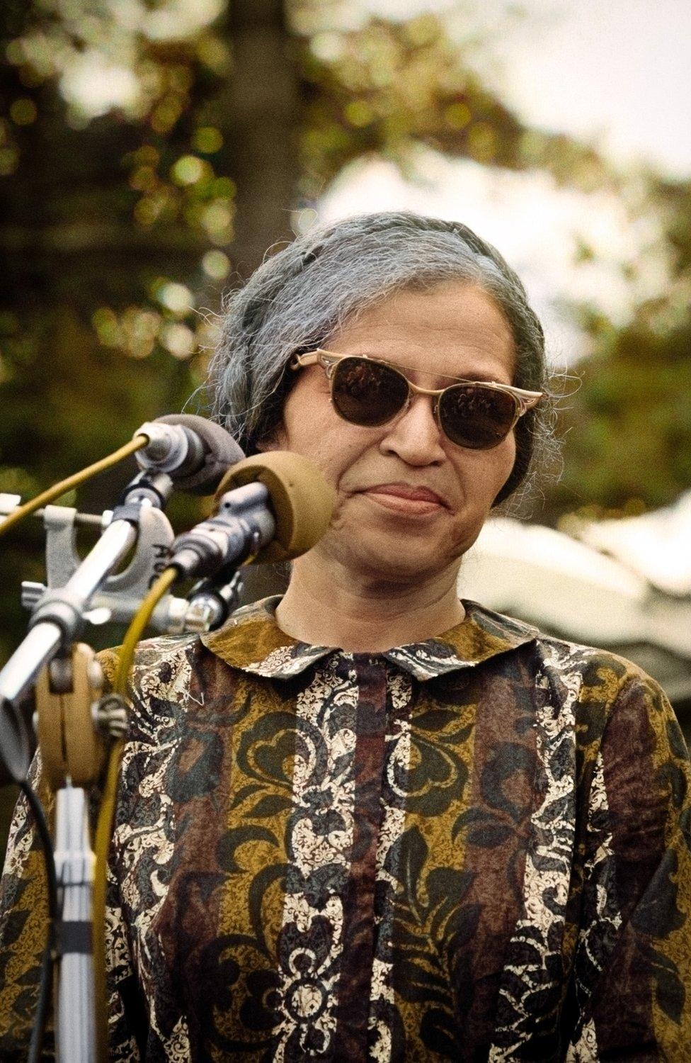 Rosa Parks stands in front of a microphone