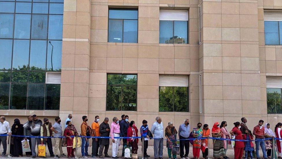 Indians waiting in a queue outside a hospital.