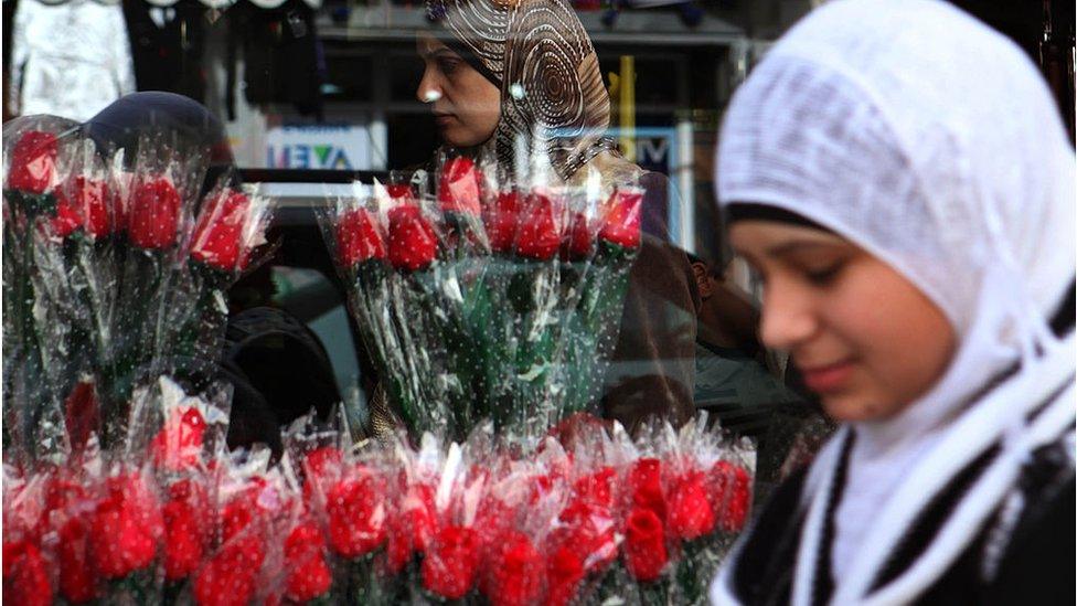 Palestinian woman in front of red roses