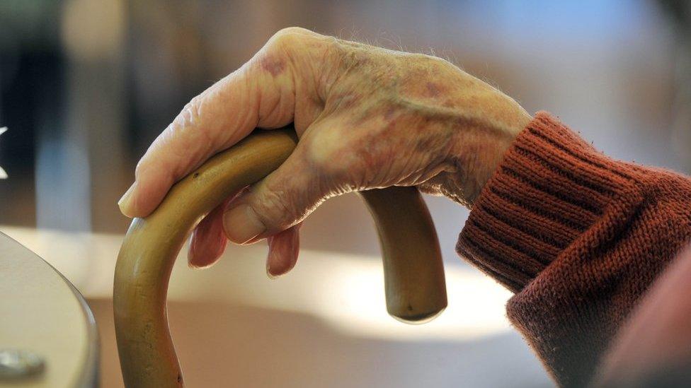 Elderly man's hand holding walking stick