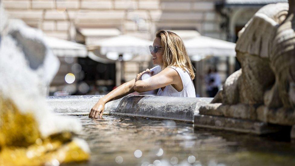 People cool off at a fountain during the heat wave in Rome, Italy