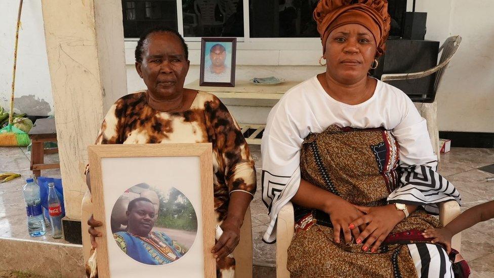 Two women holding a photograph of the dead man