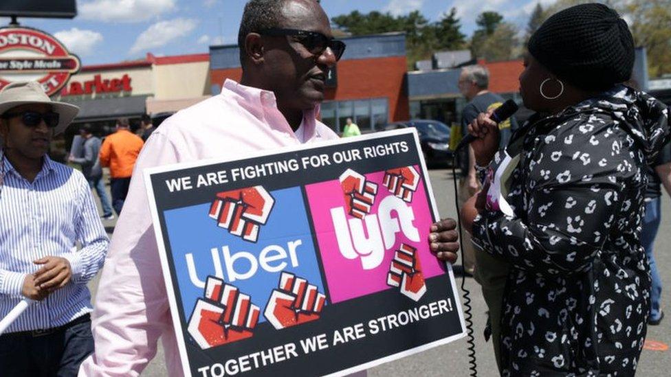 Protestor in front of Uber sign