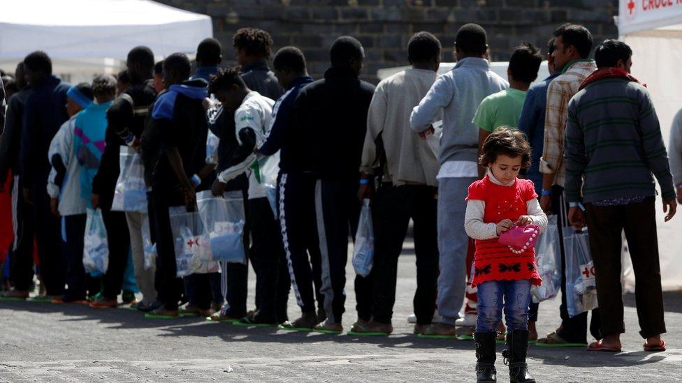 A migrant child plays with a handbag as other migrants queue to be medically checked after disembarking from the Malta-based NGO Migrant Offshore Aid Station (MOAS) ship Phoenix after it arrived with migrants and a corpse on board, in Catania on the island of Sicily, Italy, May 6, 2017