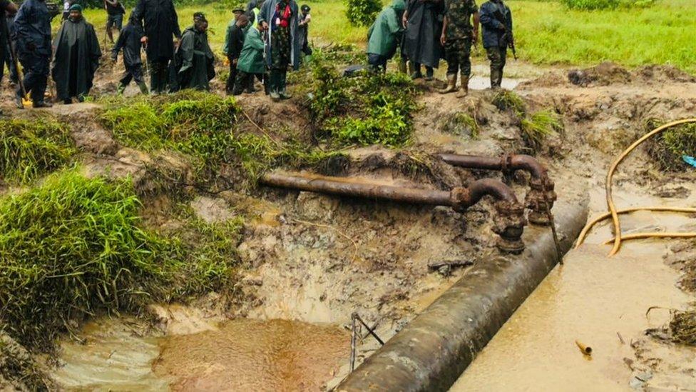 Security men stand around an oil pipiline