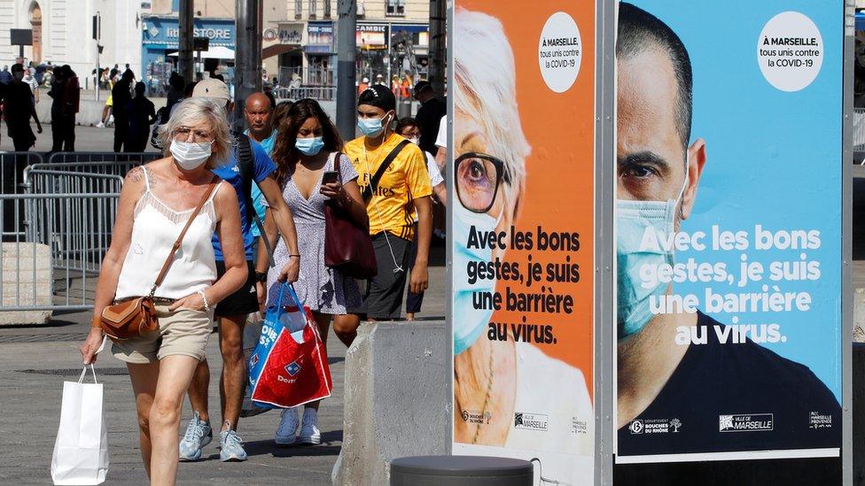 People wearing protective face masks walk near the Old Port (Vieux Port) in Marseille, France