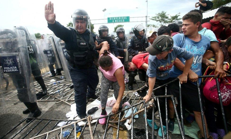 A police officer holds the arm of a Honduran migrant as she tries to cross a border checkpoint into Mexico