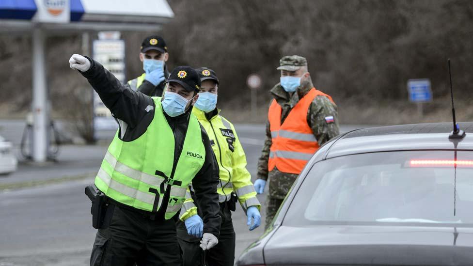 Slovakian police officers order a motorist to turn back after they refused entry to their country, at the Satorosbanya border crossing between Hungary and Slovakia, 13 March 2020. EPA