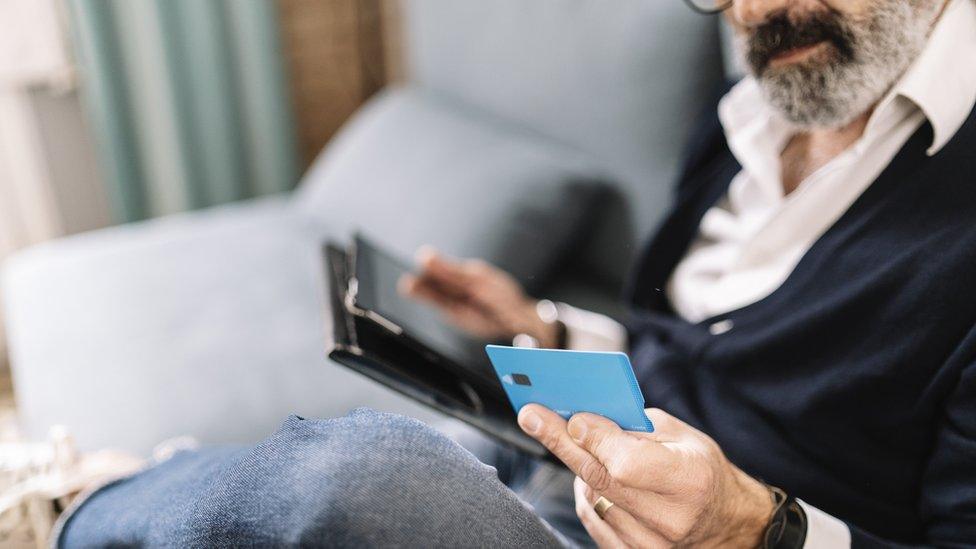 File image of a man holding a credit card and tablet