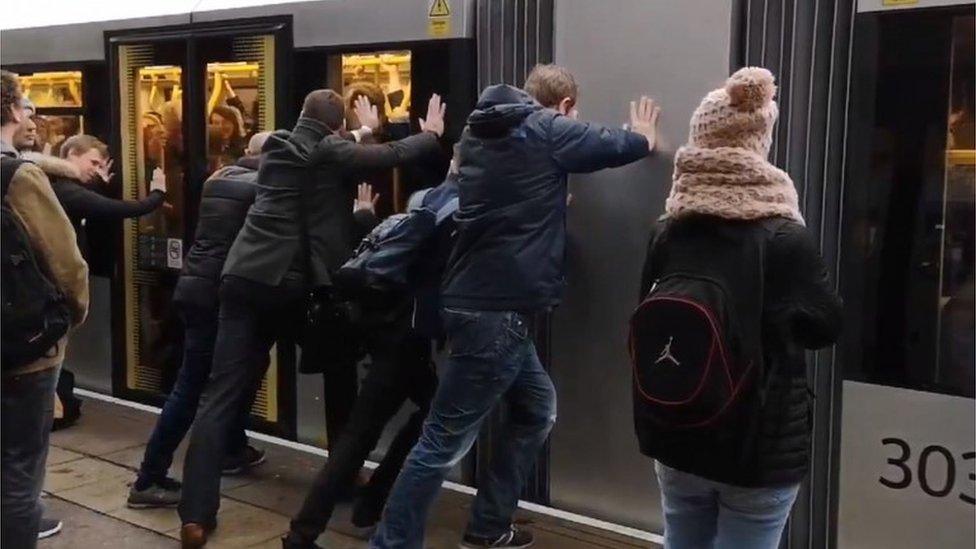 Passengers push doors shut on tram