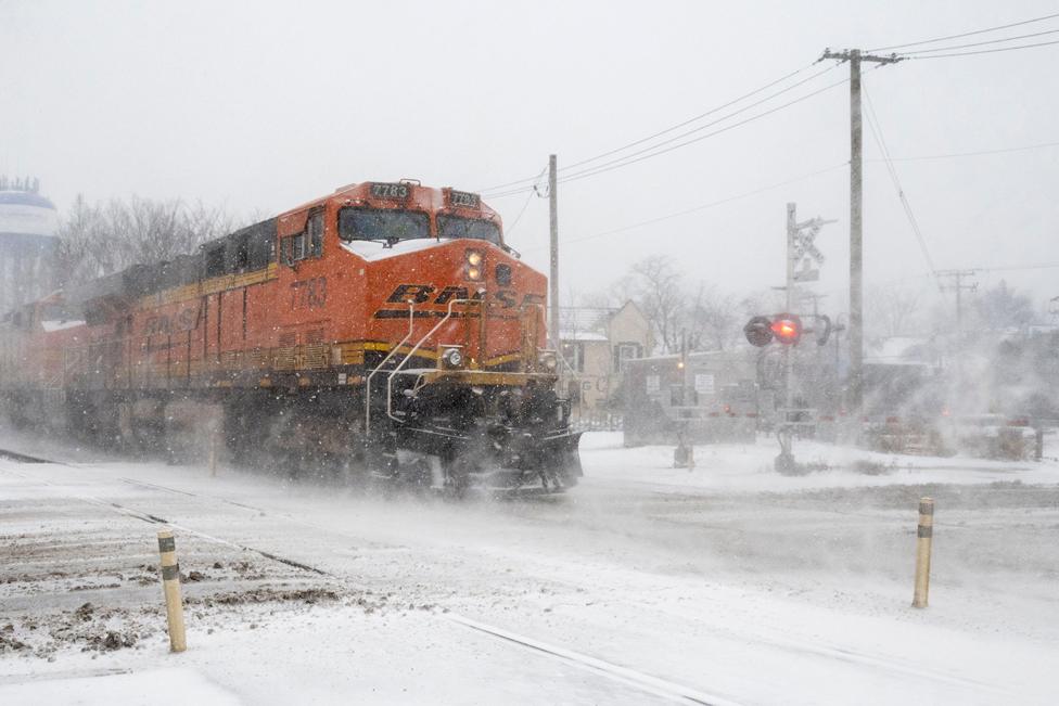 A freight train passes as heavy snowfall begins in a western suburb of Chicago as a winter storm arrives in the Midwest.