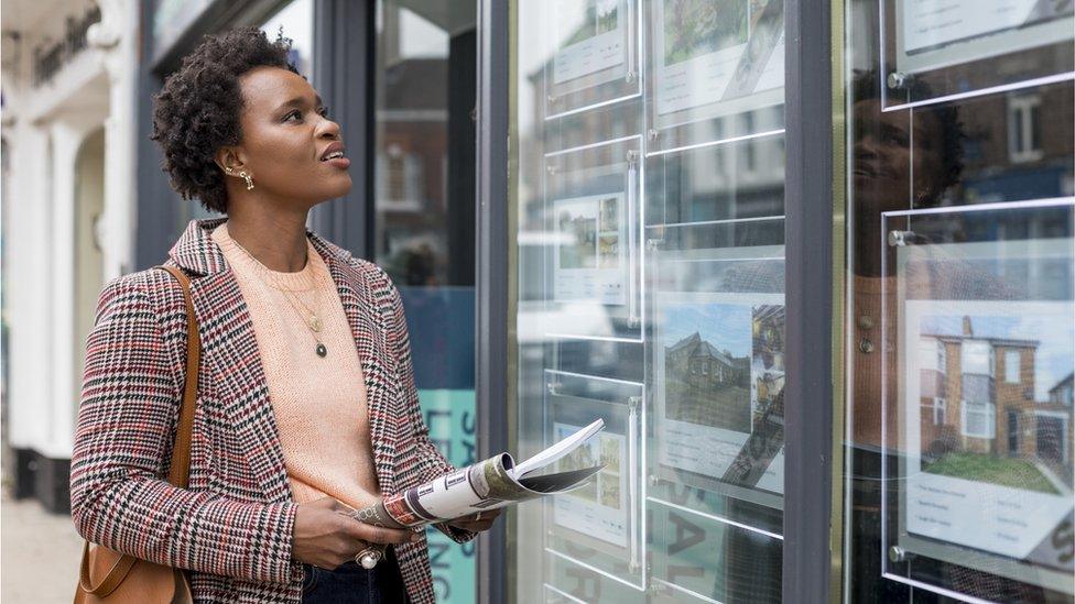 Woman looks at estate agency window - stock shot