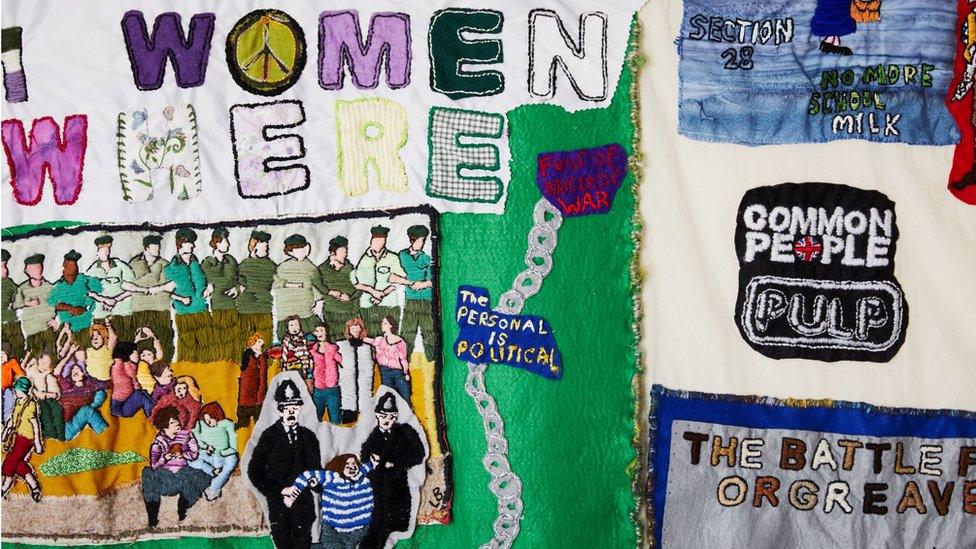 A close up of a colourful tapestry including the words Women [every[where] and Common People Pulp