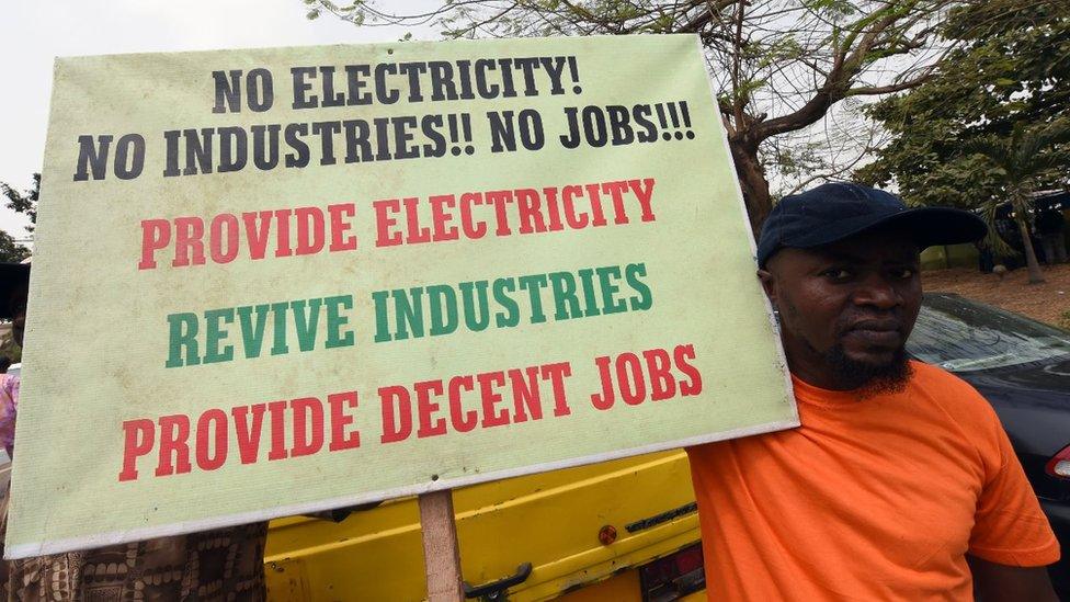 A man holds a placard reading 'No electricity! No industries!! No jobs!!! Provide electricity, revive industries, provide decent jobs' during a demonstration to protest against the 45 percent raise of electricity prices on February 8, 2016 in Lagos.