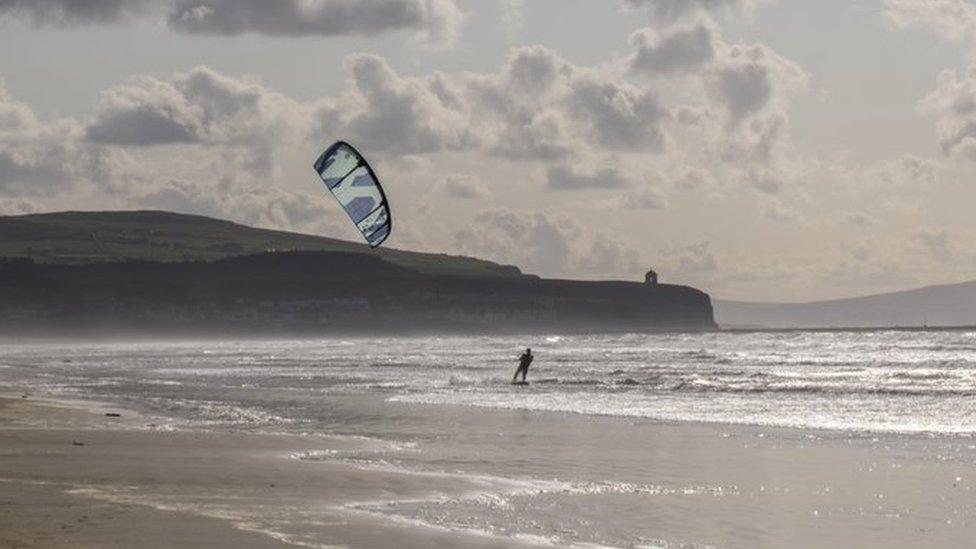 A windsurfer in the sea off Portstewart beach, in the background Mussenden Temple can be seen