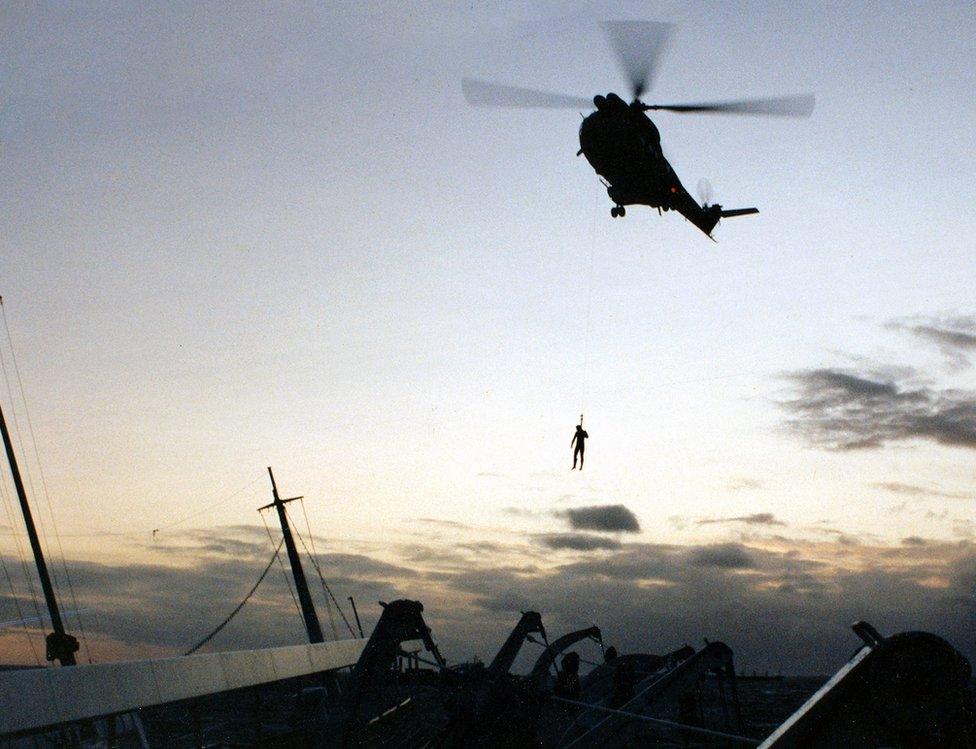 The first navy diver attempts to reach the deck of the Oceanos