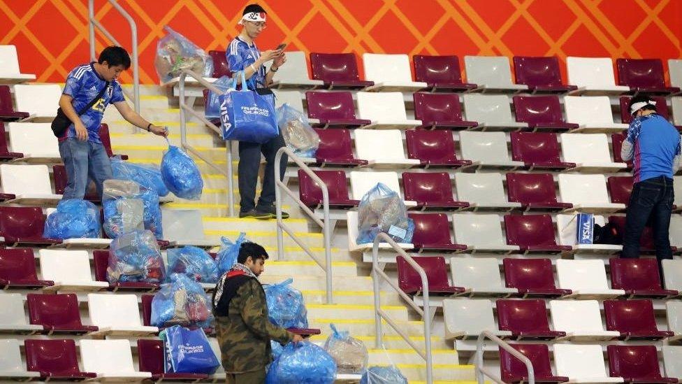 Japan fans clean the stadium