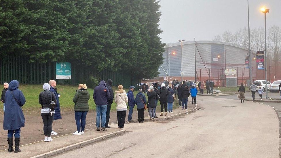 Pobl yn ciwio i gael eu brechu yn Stadiwm Cwmbrân fore Sul