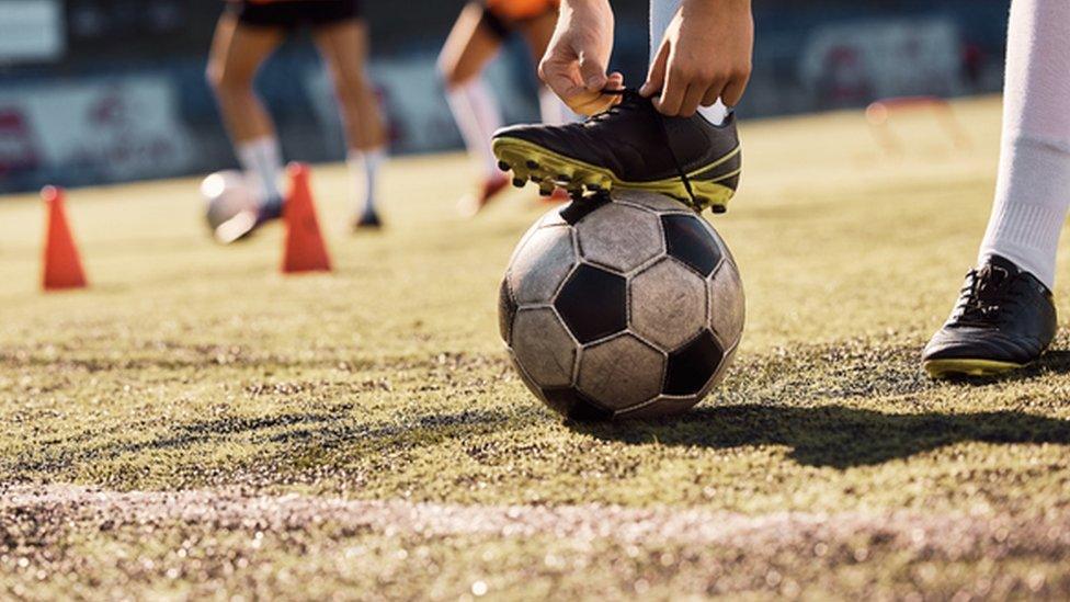 A woman's foot on top of a football