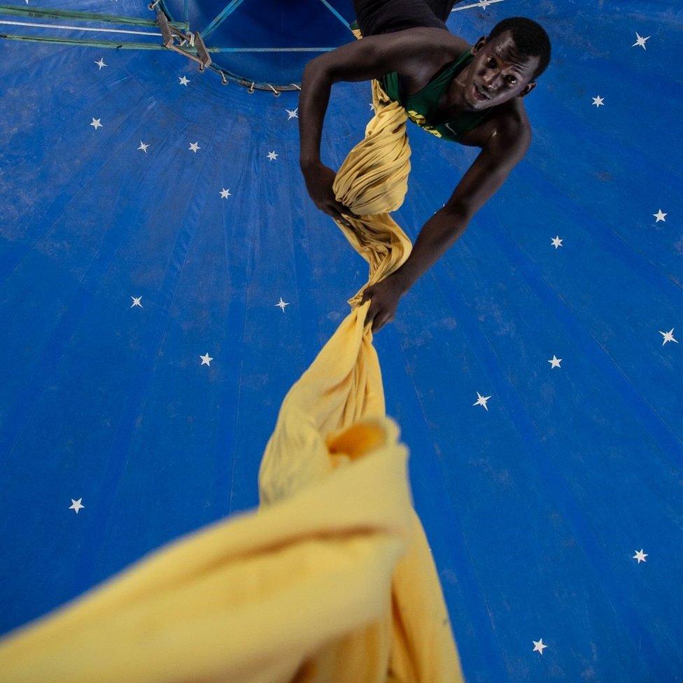 A man pulling himself up yellow draping.