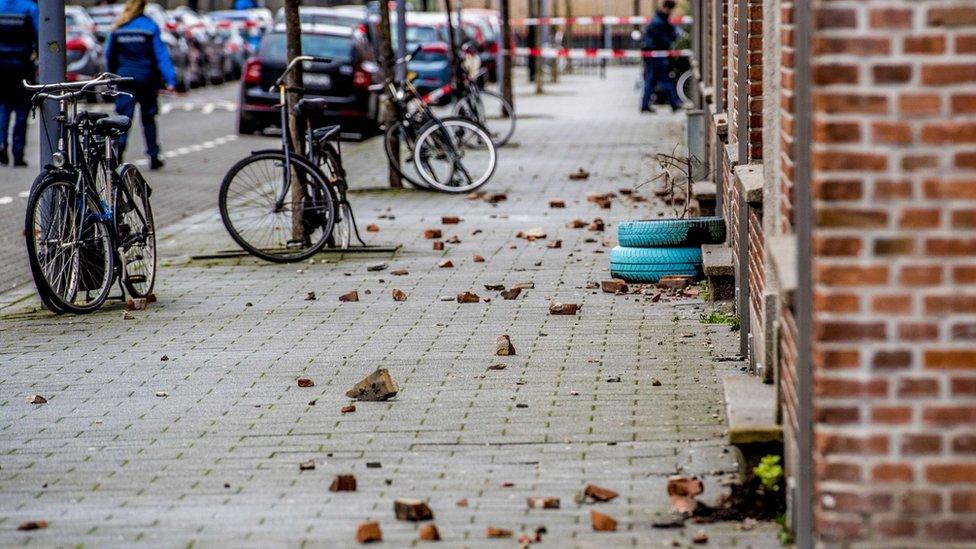 broken roof tiles across a pavement outside some terraced houses