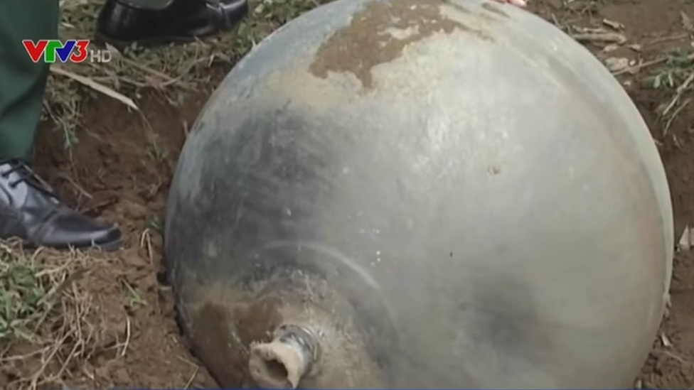 One of the metal balls in the mud, with an official's foot next to it